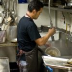 man washes dishes at a restaurant
