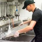 man washes dishes at restaurant