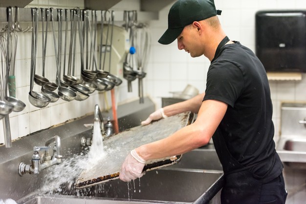 man washes dishes at restaurant