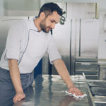 man maintains equipment in restaurant