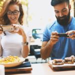 couple photographs their food in restaurant