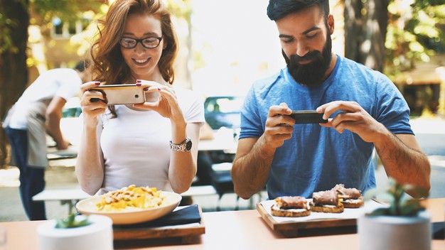 couple photographs their food in restaurant